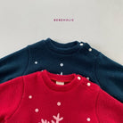 Abgebildet sind zwei Kinderpullover; der obere ist dunkelblau mit weißen Punkten und Knopfdetails auf der Schulter, und der untere ist rot mit weißen Punkten und stilisierten Baummotiven. Darüber steht in kleiner lila Schrift „Bebe Holic“ und zeigt das Star Bonnet Set von Bebe Holic für die Kleinen.